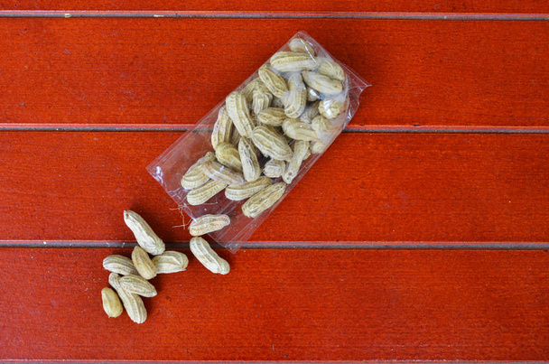 Орехи в прозрачном мешке на красном деревянном полу
. - Фото, изображение
