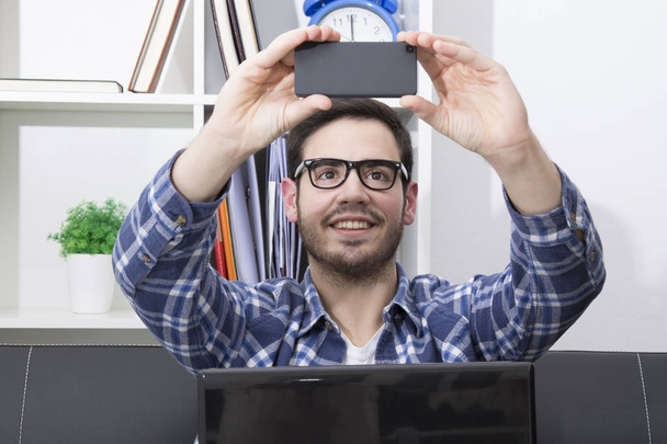Man in the office doing a selfie with his cell phone - Foto, Imagen