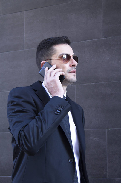 Man in suit and sunglasses talking to cellphone - Фото, изображение