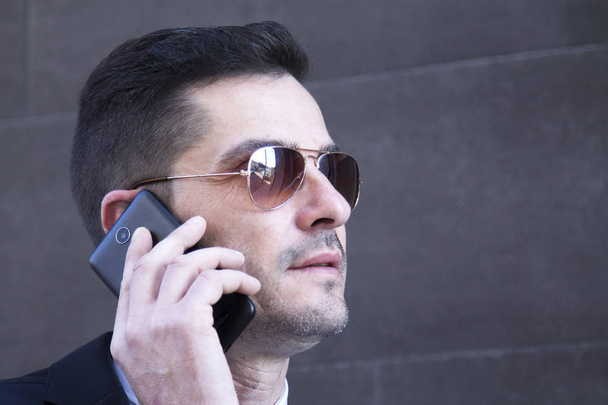 Erkek takım elbise ve cep telefonu için konuşmaya güneş gözlüğü - Fotoğraf, Görsel