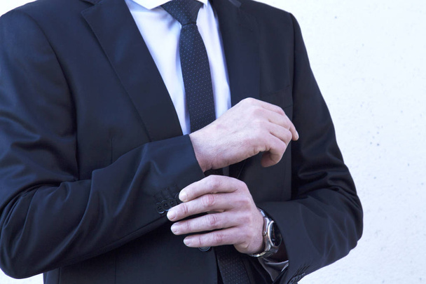 Portrait of man in suit and sunglasses tying buttons - Fotó, kép