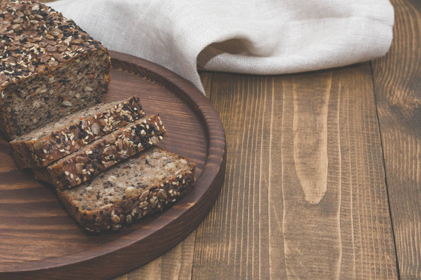 Fitness bread. A loaf of fresh rustic whole meal rye bread, sliced on a wooden board, rural food background. Top view. Fitness bread. Copy space. - Photo, Image