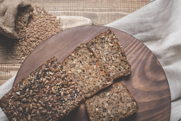 Fitness bread. A loaf of fresh rustic whole meal rye bread, sliced on a wooden board, rural food background. Top view. - Photo, Image