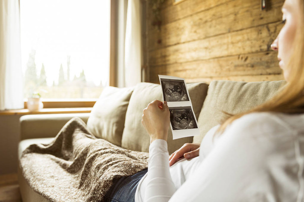 Mulher grávida esperando recém-nascido e segurando ultra-som enquanto ly
 - Foto, Imagem