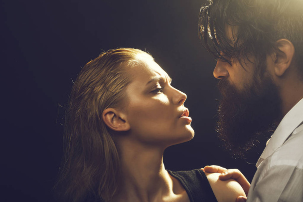 young sexy couple of pretty woman with blonde wet hair and handsome bearded man with long beard embracing on dark studio background - Zdjęcie, obraz