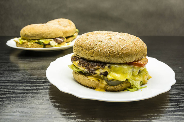 Beef burger on a white plate on a wooden background. - Photo, Image