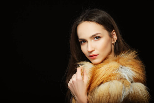 Portrait of beautiful happy girl with natural makeup in fluffy fur coat on black background - Фото, зображення