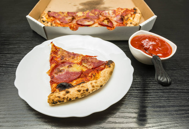 Portion of pizza on a plate and ketchup in a bowl. - Photo, Image