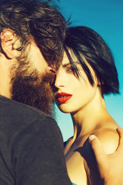 young sexy couple of brunette woman with red lips on pretty face and handsome bearded man on summer sunny day on nature on blue sky background - Foto, immagini