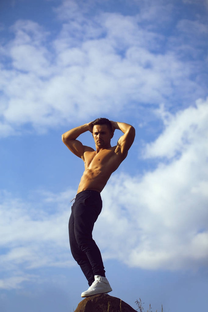 Sexy muscular man on sky background - Foto, Imagem