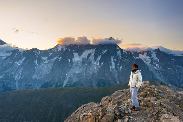 Mujer observando el impresionante amanecer sobre valles, crestas y picos de montaña. Amplia vista desde 3000 m en Valle d 'Aosta. Aventuras de verano en los Alpes italianos
. - Foto, Imagen