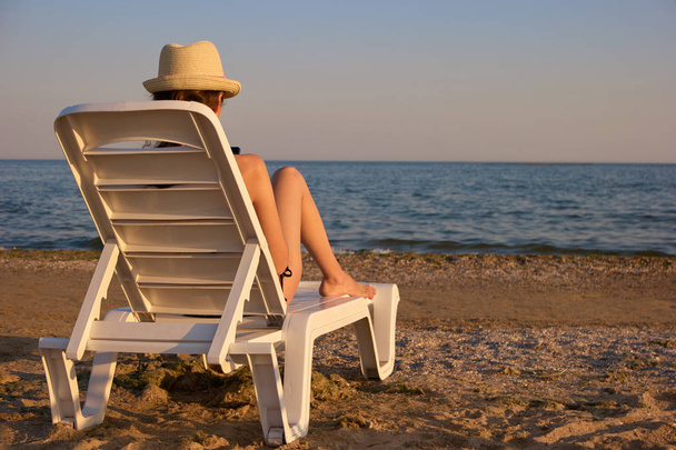 Mujer chateando smartphone en chaise longue en la playa
. - Foto, imagen