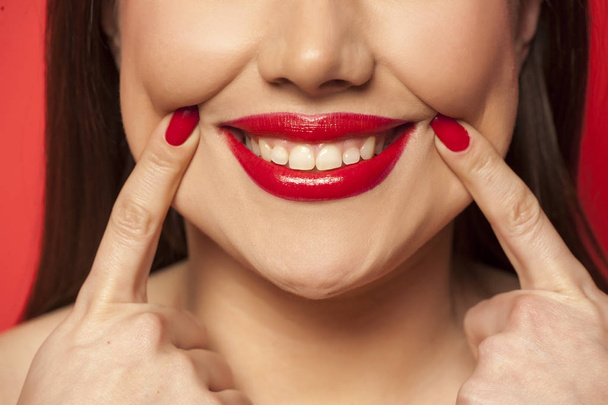 Žena, nutí její úsměv s prsty - Fotografie, Obrázek