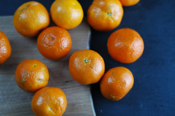 Neoloupané mandarinky na tmavém pozadí s tvrdé světlo. - Fotografie, Obrázek