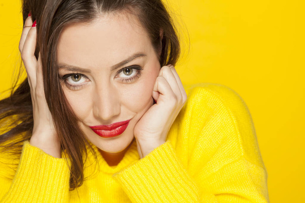 Beautiful sexy woman in yellow sweater on a yellow background - Фото, изображение