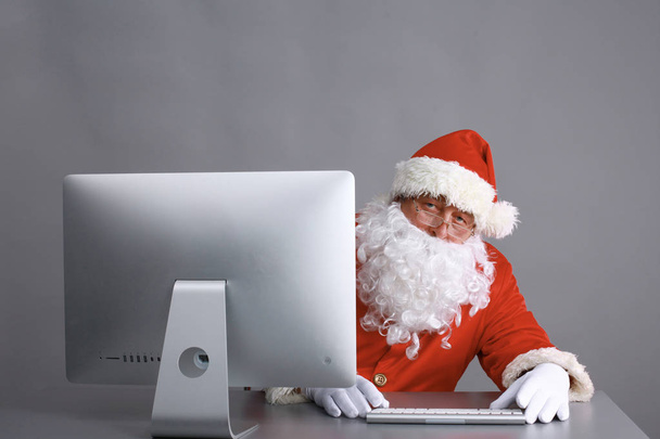 Santa Claus reading children letters and writing responses to them using laptop . - Foto, Imagem