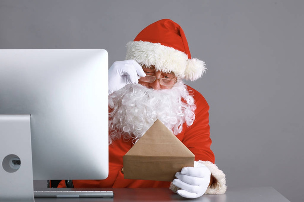 Santa Claus reading children letters and writing responses to them using laptop . - Фото, зображення
