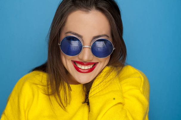 Kaunis hymyilevä nainen sininen aurinkolasit ja keltainen pusero
  - Valokuva, kuva