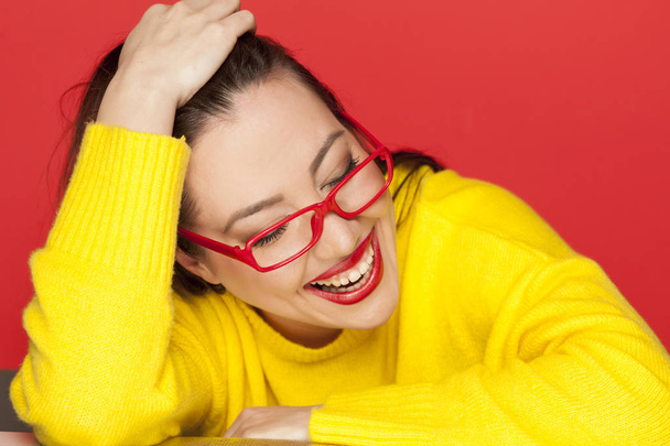 schöne, glückliche Frau mit roter Brille auf rotem Hintergrund - Foto, Bild