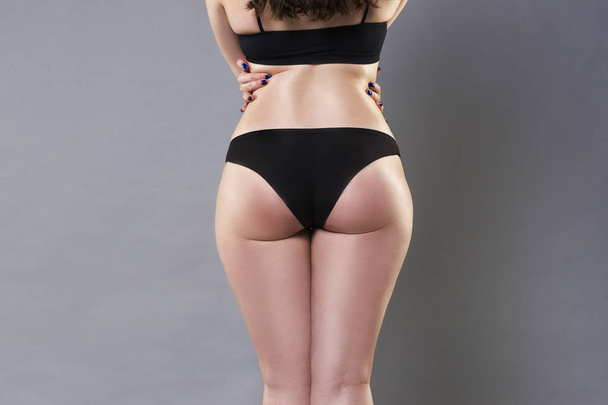 Woman in black underwear on gray background, cellulite on female buttocks - Foto, imagen