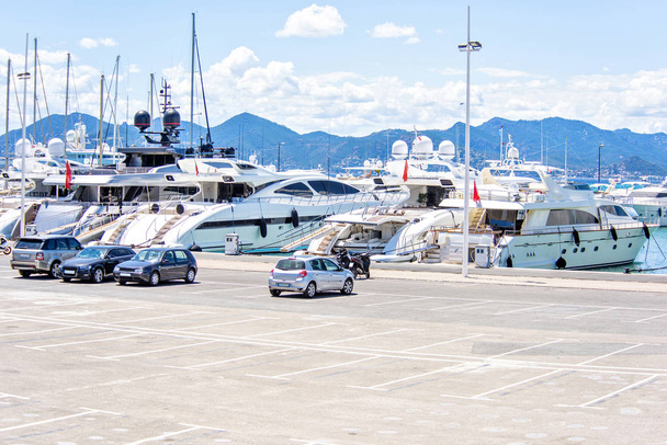 Денний вигляд на паркінг з машинами і великими розкішними яхтами
 - Фото, зображення