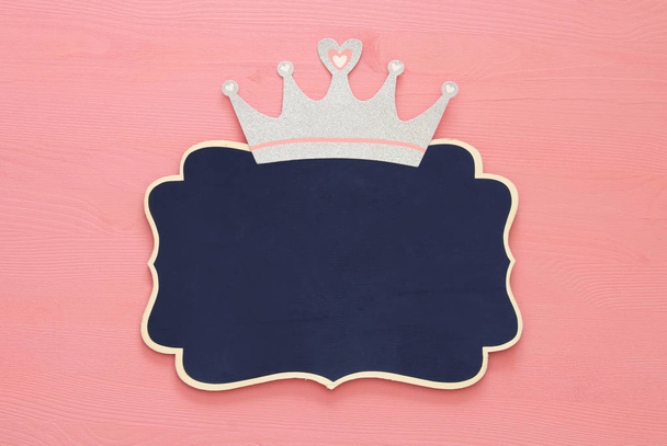 top view image of silver glitter crown and blackboard over pink wooden background. - Φωτογραφία, εικόνα