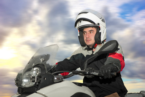 Молодой человек сидит на мотоцикле и с шлемом на голове
 - Фото, изображение