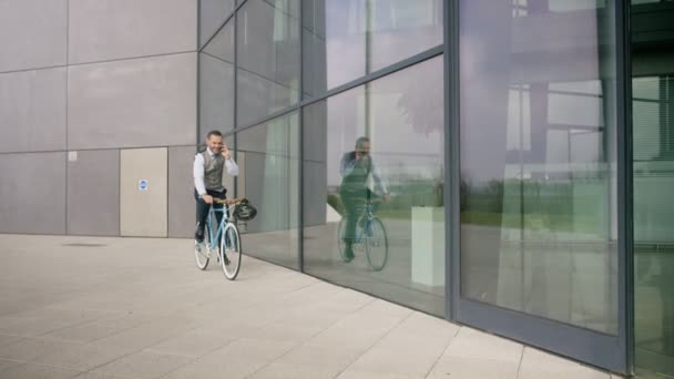 4K Businessman with bicycle talking on cell phone before entering office - Filmagem, Vídeo