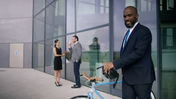 4K Cheerful businessman with bicycle leaving office building - Filmati, video