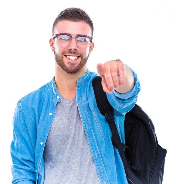 A male student with a school bag holding books and pointing you isolated on white background - Foto, Imagen