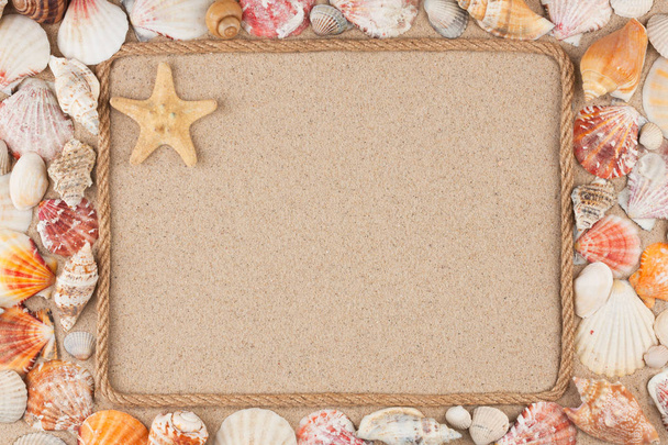 Beautiful frame made of rope and star, sea shells on the sand, with place for your image, text. - Photo, Image