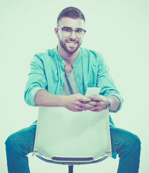 Young man sitting on the chair isolated over white background - Φωτογραφία, εικόνα
