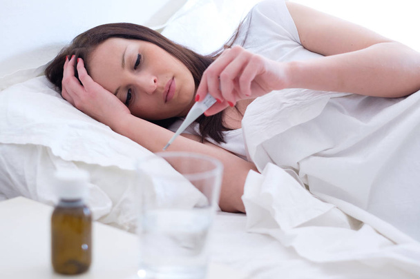 Άρρωστη γυναίκα αισθάνεται άσχημα και ξαπλωμένη στο κρεβάτι - Φωτογραφία, εικόνα