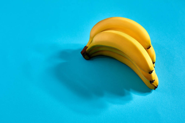 Gele rijpe bananen op blauwe achtergrond met ruimte voor tekst of ontwerp. Bovenaanzicht - Foto, afbeelding