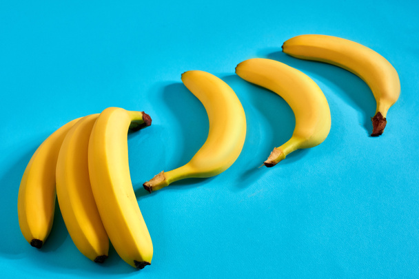 Plátanos amarillos maduros sobre fondo azul con espacio para texto o diseño. Vista superior
 - Foto, Imagen