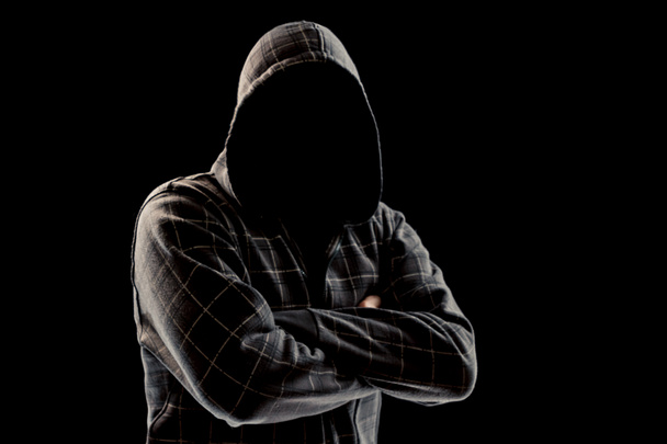Silhouette di un uomo in un cappuccio su uno sfondo nero, il suo volto non è visibile, ha incrociato le braccia sul petto. Il concetto di criminale, in incognito, mistero, segretezza, anonimato
. - Foto, immagini
