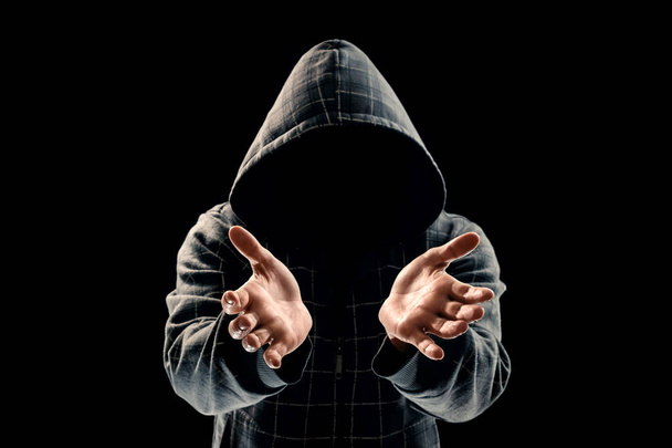 Silhouette of a man in a hood on a black background, the face is not visible, shows the palms in the camera. The concept of the criminal is given, incognito, secret, secrecy, anonymity. - Foto, immagini