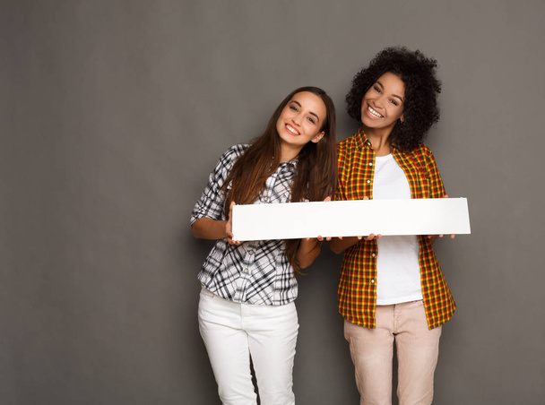 Two girlfriends holding blank white banner - Fotó, kép
