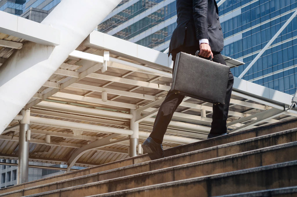 young handsome business man holding briefcase and walking up the stairs going to work time at morning in the city, determination, confidence, lifestyle, rush hour, grow up and successful concept - Foto, Imagen