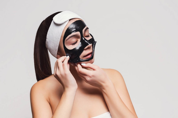 Young girl with purifying black face mask - Фото, изображение