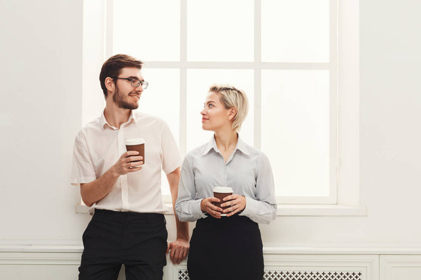 Couple of young colleagues drink coffee near window - Photo, Image