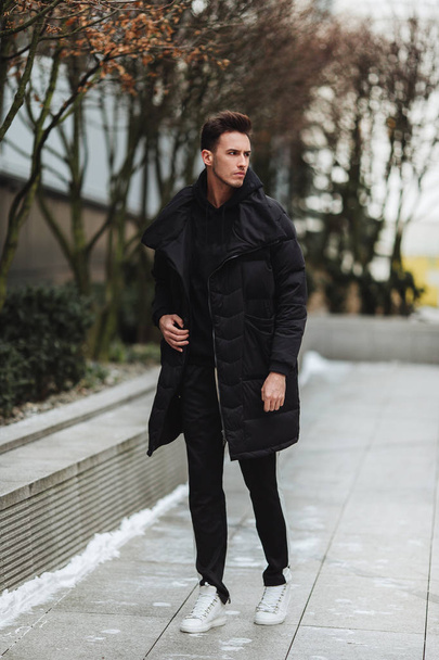 Stylish man wolk on the street. Winter cold outfit. Big jacket w - Фото, зображення