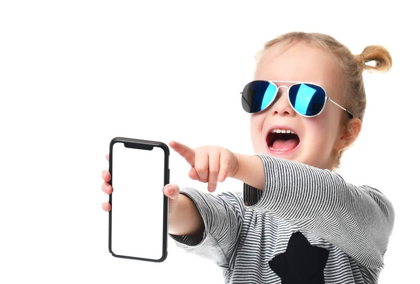 Little girl kid in blue aviator sunglasses showing blank screen of mobile phone shouting - 写真・画像