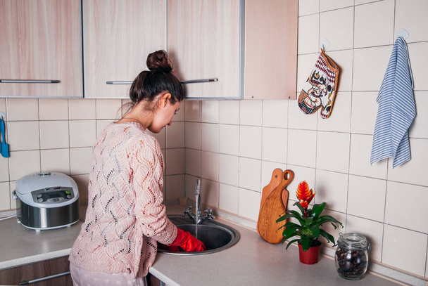 Young woman washing the dishes in modern kitchen. - Фото, изображение