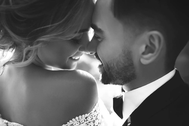 Bride and groom kisses tenderly in the shadow of a flying veil .beautiful pictures. guys enjoy. Sexy kissing stylish couple of lovers close up portrait . black and white - 写真・画像