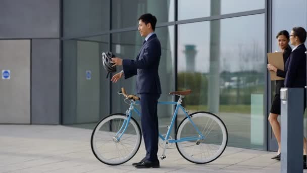 4K Asian businessman with bicycle leaving office at end of day and coworkers following - Imágenes, Vídeo