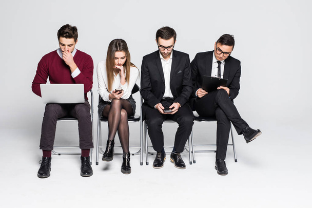 Young people are sitting in a row in business centre while waiting for the interview isolated on white - Photo, Image