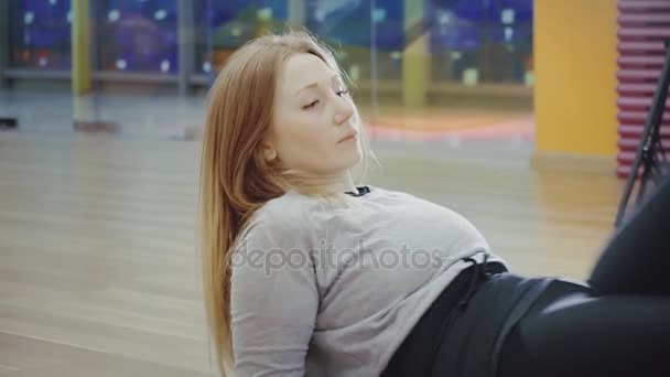 Blonde pretty young woman lying and doing splits in the gym. - Video