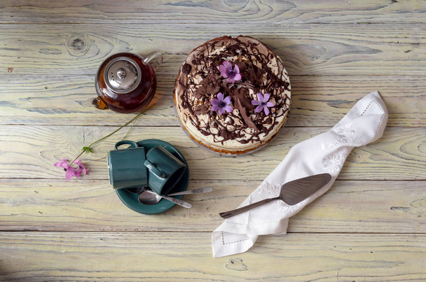 Σπιτικό, νόστιμο, ολόκληρο κέικ, τσαγιέρα με το τσάι και κύπελλα σε ένα κοντινό πλάνο ξύλινο τραπέζι. - Φωτογραφία, εικόνα