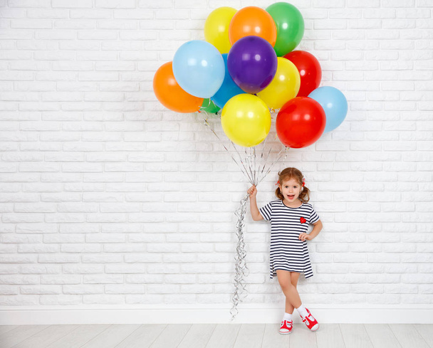 Happy funny child girl with  colorful balloons near an brick wal - Foto, Bild